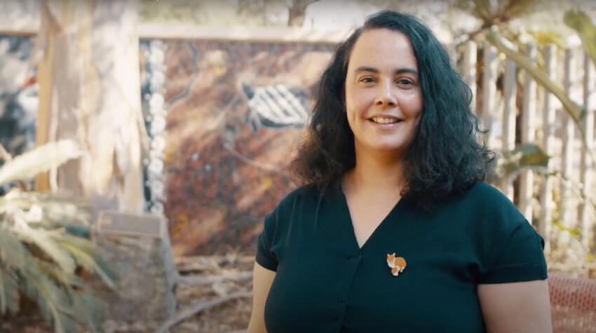 Tonia is standing outside, looking at the camera, smiling.