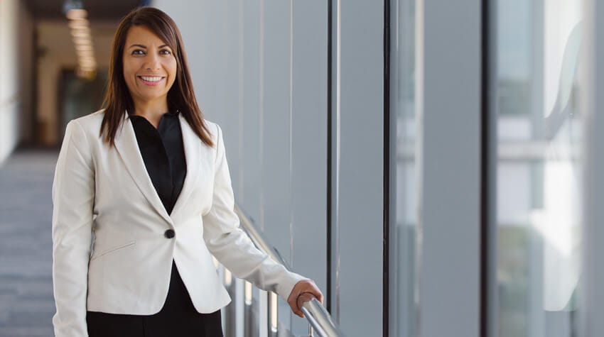 Professional woman smiling in a modern office corridor.