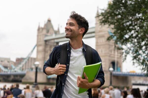 Man with books in front of London Bridge